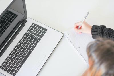 Woman taking notes at laptop