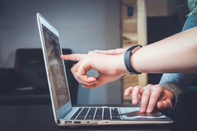 Hands pointing towards a laptop screen by John Schnobrich on Unsplash