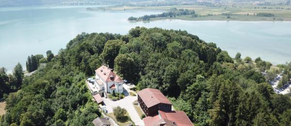 A small castle perched high on a hill overlooking a lake