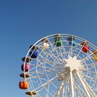 Rainbow coloured ferris wheel with a blue sky background by Andrea Enríquez Cousiño on Unsplash