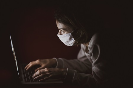 woman in mask working on laptop